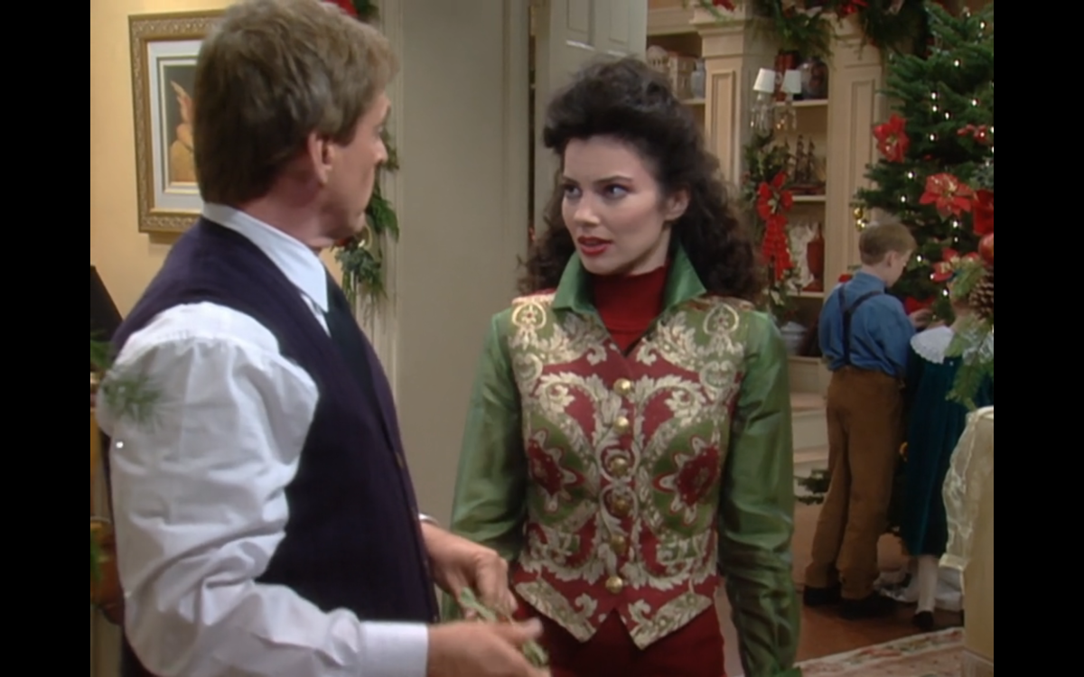 Fran Fine dressed in a green and red vest talking to Niles, the butler.